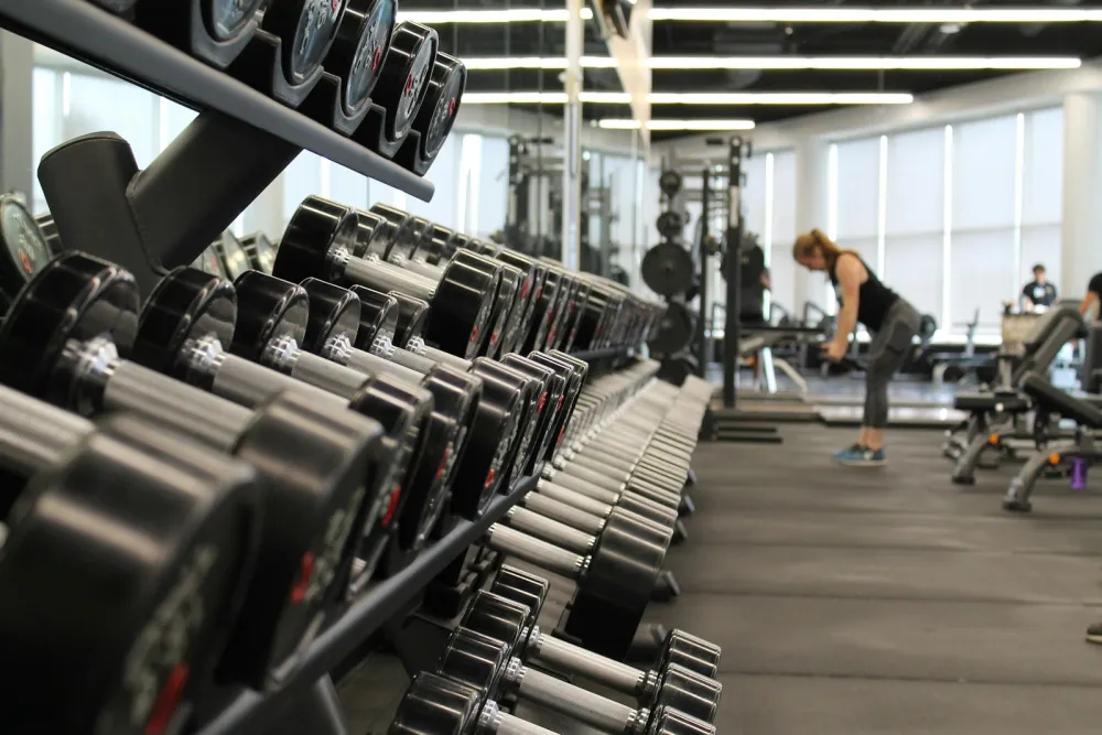 A working gym with dumbbells in the foreground and members training