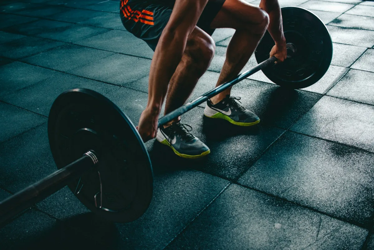 An athlete setting up for a barbell lift on the gym floor